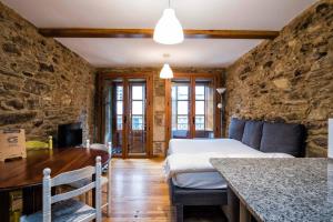 1 dormitorio con cama y pared de piedra en Alda Fogar Natural, en Santiago de Compostela