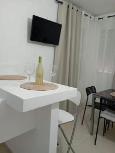 Apartamento Aimar Barbate في بارباتي: طاولة بيضاء مع كأسين من النبيذ وتلفزيون