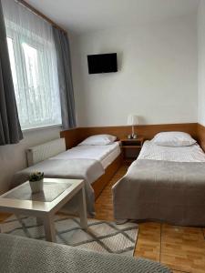 a bedroom with two beds and a tv on the wall at Pensjonat Melodia in Pobierowo