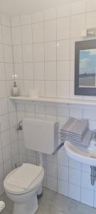 een witte badkamer met een toilet en een wastafel bij Haus Rückenwind Rückenwind, Lütjeoog in Norderney