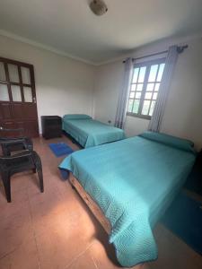 a bedroom with two beds and a chair in it at Casa Amigable y Confortable in Yacuiba