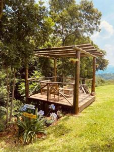 a wooden deck with a pergola in a field at Refúgio do Sol Park Pousada - Cabana - Hospedagem 