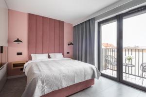 a bedroom with a large bed and a balcony at AVAPARTS Apartament ROSE in Jastarnia