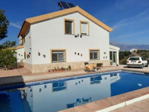 a villa with a swimming pool in front of a house at Casa Montaña Vélez-Málaga B&B in Vélez-Málaga