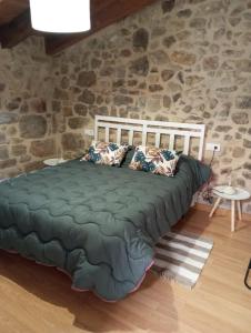 Cama en habitación con pared de piedra en L'esgorfa d'Arnes, en Arnes