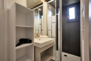 un bagno bianco con lavandino e specchio di Le Chalet Aquila - Welkeys a Saubrigues Altre 5 foto