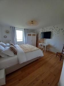 a white bedroom with a large bed and a television at L'Escale de Beauregard in Coublevie