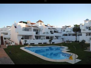um grande edifício de apartamentos branco com uma piscina em Luxury Hacienda Golf Islantilla em Islantilla