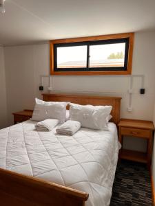 a bedroom with a large white bed with a window at Hostal B&B Coastal Natales in Puerto Natales