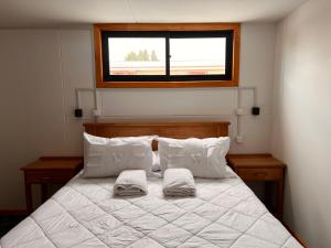 a bedroom with a bed with two pillows and a window at Hostal B&B Coastal Natales in Puerto Natales