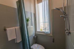 a bathroom with a toilet and a window and a shower at Hotel Atlas in Cesenatico