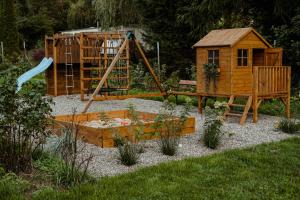 um parque infantil num jardim com uma casa de madeira em Zacisze em Morawica