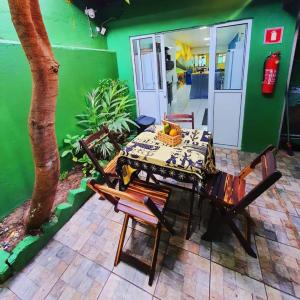 uma mesa e cadeiras num quarto com uma parede verde em Pousada Hostel Mar e Sertão em Maceió