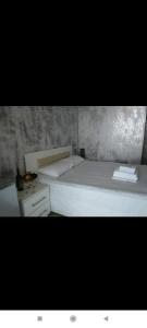Geno Guest House في كفارياتي: غرفة نوم بسرير ابيض وموقف ليلي