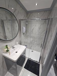 a white bathroom with a shower and a sink at Hot tub hideaway in Manchester