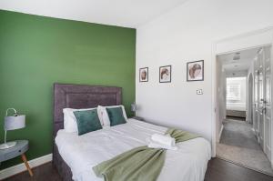 sypialnia z łóżkiem i zieloną ścianą w obiekcie Stylish 3 BR House close to Streatham Hill station w Londynie