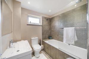 ein Badezimmer mit einer Badewanne, einem WC und einem Waschbecken in der Unterkunft Stylish 3 BR House close to Streatham Hill station in London