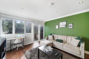 uma sala de estar com um sofá branco e paredes verdes em Stylish 3 BR House close to Streatham Hill station em Londres