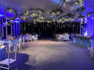 a banquet hall with white tables and chairs and lights at Райски кът in Kalofer