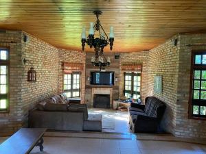 a living room with a brick wall and a chandelier at Casa de campo para relaxar em meio à natureza! in Treze de Maio