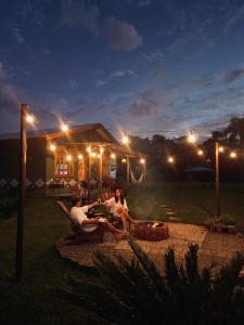 a group of people sitting around a fire pit at night at Refúgio do Sol Park Pousada - Cabana - Hospedagem 