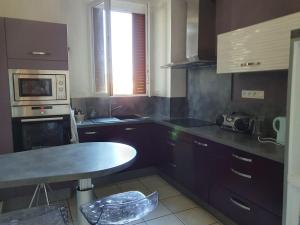 a kitchen with a table and a microwave at Spacieux 80 m2 Cœur de Vichy proche des Thermes in Vichy +2 photos