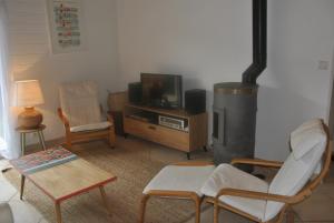 a living room with a couch and chairs and a tv at Belle maison avec vue et jardin au Chateau d'Oleron in Le Château-dʼOléron