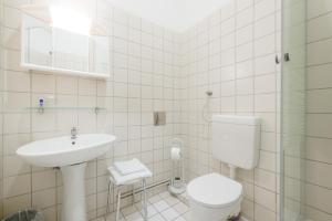 a white bathroom with a toilet and a sink at Pension Votiv in Vienna