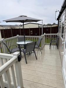 une terrasse avec une table, des chaises et un parasol dans l'établissement North Shore, Skegness, new 8 berth caravan, à Lincolnshire