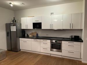 a kitchen with white cabinets and a stainless steel refrigerator at Luxusapartment Hamburg Hafencity in Hamburg