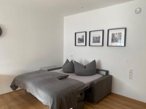a bed in a white room with three pictures on the wall at Apart Mark, Stanz bei Landeck - Moderne Wohnung in sonniger Lage in Stanz bei Landeck