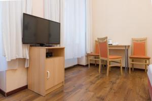 a room with a television on a stand with two chairs at Pension Votiv in Vienna