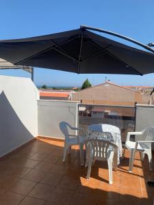 um pátio com uma mesa, cadeiras e um guarda-sol em Belle maison de vacances em Grao de Castellón