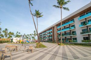 um edifício com mesas e cadeiras e palmeiras em Maceio Mar Resort All Inclusive em Maceió