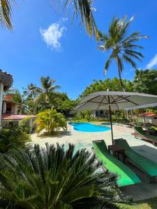 un resort con piscina, ombrellone e palme di Pousada Les Alizes a Icaraí