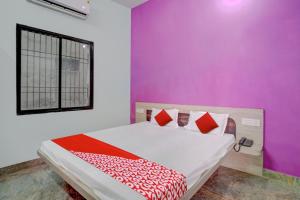 um quarto com uma cama com uma parede roxa em OYO Flagship 81389 Hotel Siddhi Vinayak em Motīhāri