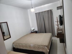 a small bedroom with a bed and a mirror at Village Verano Guarajuba in Guarajuba