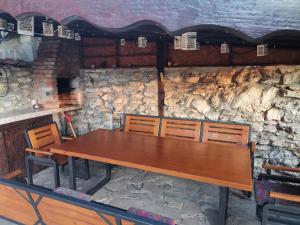 een houten tafel en stoelen voor een stenen muur bij Sunset House in Varna