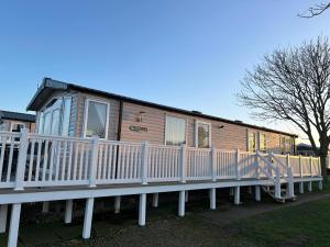a wooden house with a white fence in front of it at Sea view luxury caravan in Filey