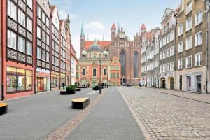 an empty city street with buildings and a clock tower at Grobla -Old Town by Grand Apartments in Gdańsk