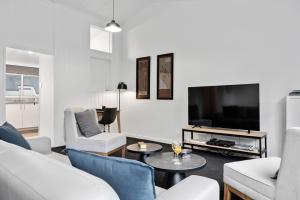 a living room with white furniture and a flat screen tv at The Tauranga on the Waterfront in Tauranga