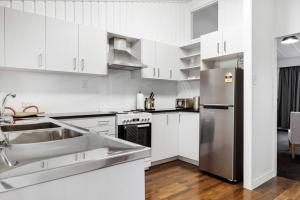 uma cozinha com armários brancos e um frigorífico de aço inoxidável em The Tauranga on the Waterfront em Tauranga