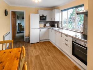 een keuken met witte apparatuur en een houten vloer bij Bournstream Cottage in Withycombe