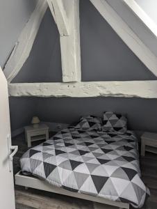 ein Schlafzimmer mit einem schwarz-weiß karierten Bett in der Unterkunft charmante maison Normande in Livarot