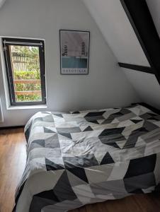 Schlafzimmer mit einem schwarzen und weißen Bett und einem Fenster in der Unterkunft charmante maison Normande in Livarot
