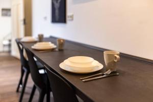 einen langen Tisch mit Tellern, Tassen und Küchenutensilien in der Unterkunft Design Altstadtperle mit 2,5 Schlafzimmer- Waschmaschine - Parkplatz in Pirna