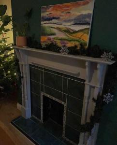 a fireplace in a living room with a painting on the wall at Cosy Gem in the heart of Glossop in Glossop