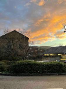 a cloudy sky with a building in the foreground at Cosy Gem in the heart of Glossop in Glossop