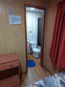 a bathroom with a toilet and a door to a room at Hostal Prat 2 in Valdivia
