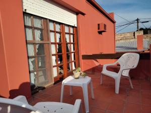 un patio con 2 sillas, una mesa y una ventana en La Escondida, Casa de Huéspedes en San Antonio de Areco